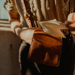 Load image into Gallery viewer, Male Model holding a Leather Wallet with folded paper inside. Leather Suspenders. Milwaukee. Directive
